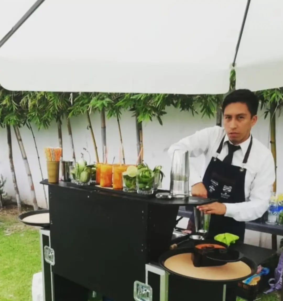  Barman profesional con uniforme, detrás de una barra sencilla, preparando bebidas con botellas proporcionadas por el cliente.